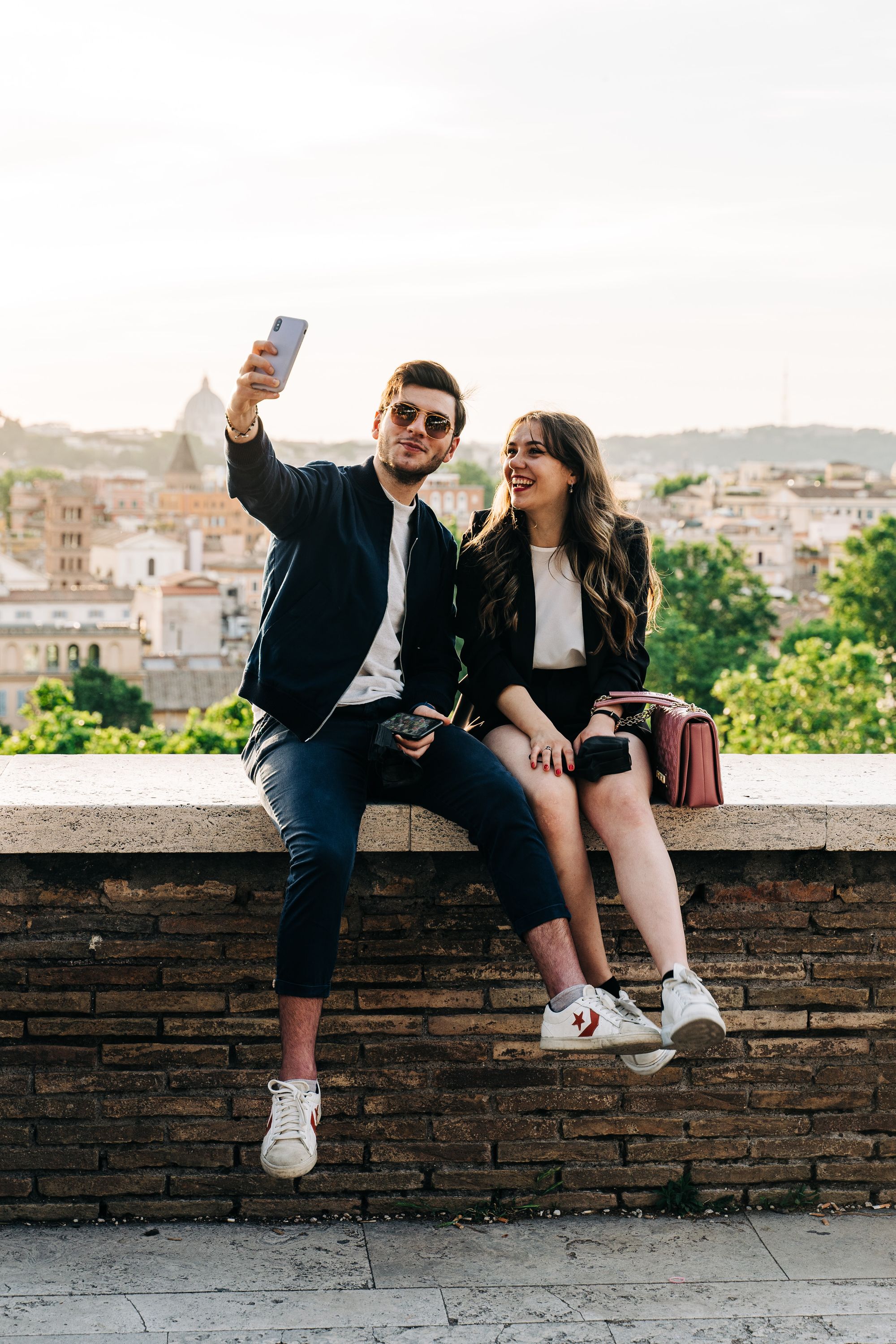 siedząca na murku para robi sobie selfie