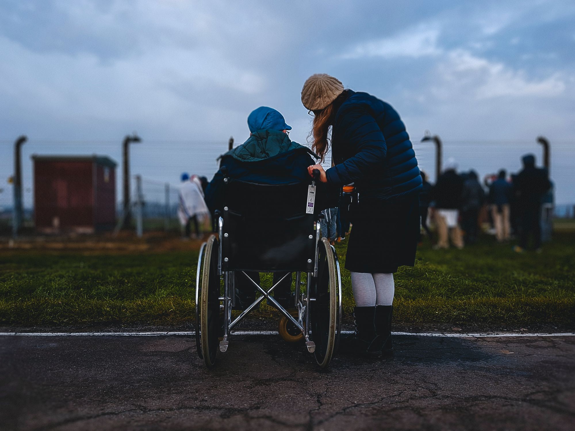 kobieta pochyla się nad osobą na wózku inwalidzkim 