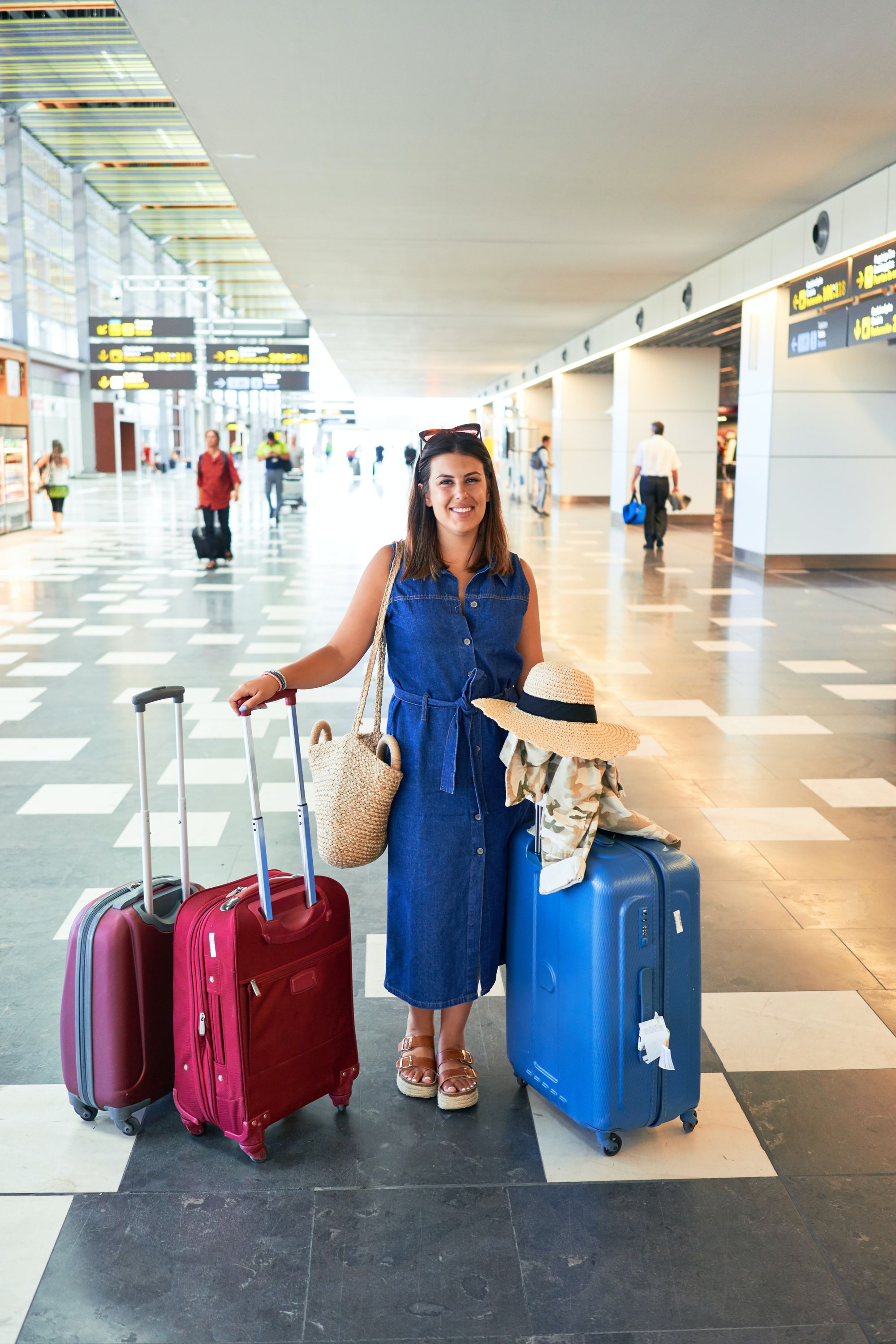 kobieta stojąca na lotnisku z walizkami