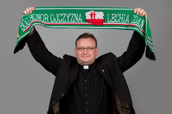 Ksiądz Jarosław Wąsowicz trzymający uniesiony w górę szalik Lechii Gdańsk